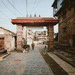 A historic Nepalese archway in a vibrant urban street, showcasing traditional architecture.