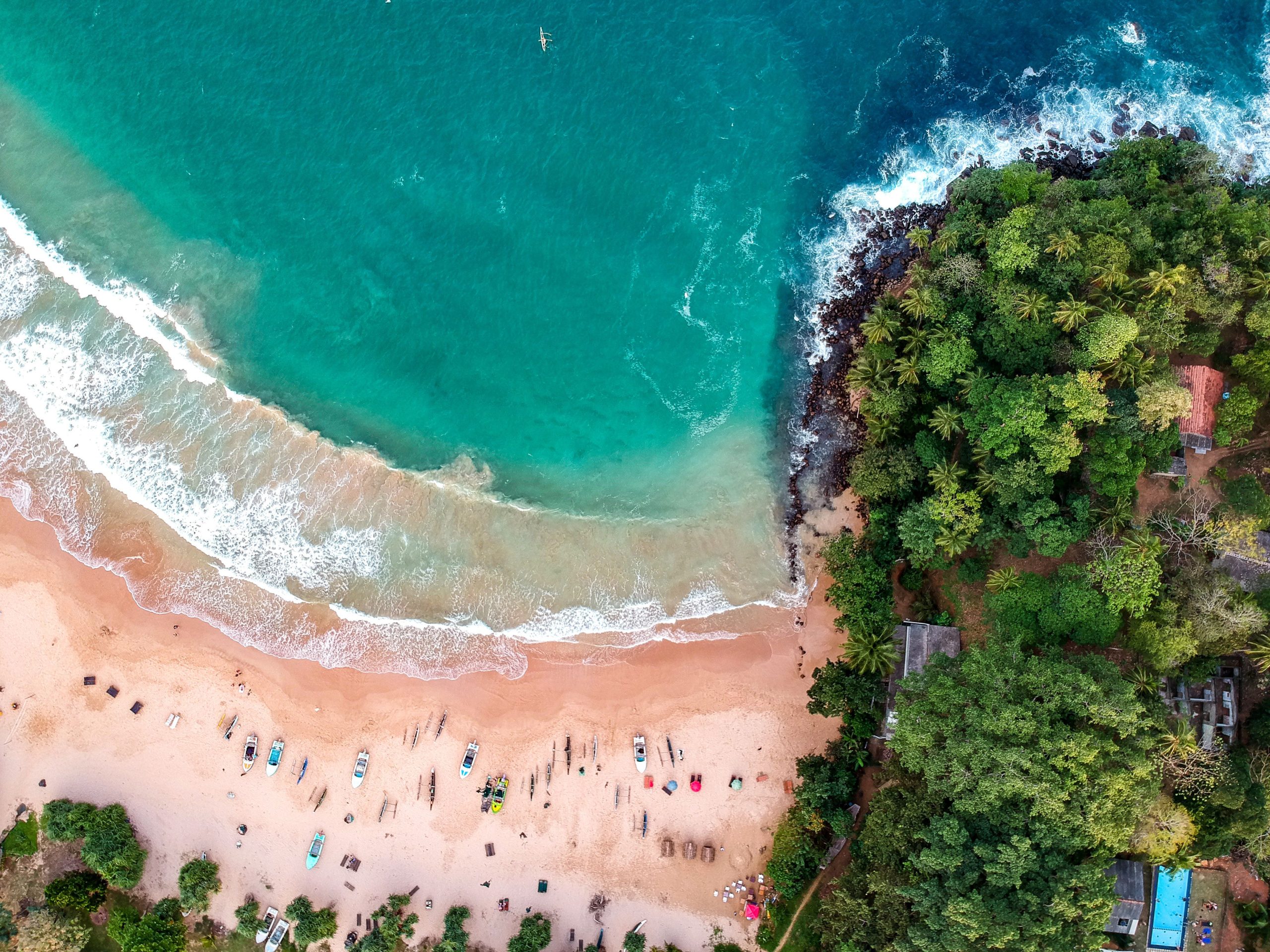 A stunning aerial shot of a vibrant tropical beach in Sri Lanka with lush greenery and turquoise waters.