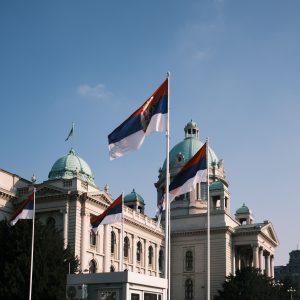 Serbian parliament building with national flags on a clear day.