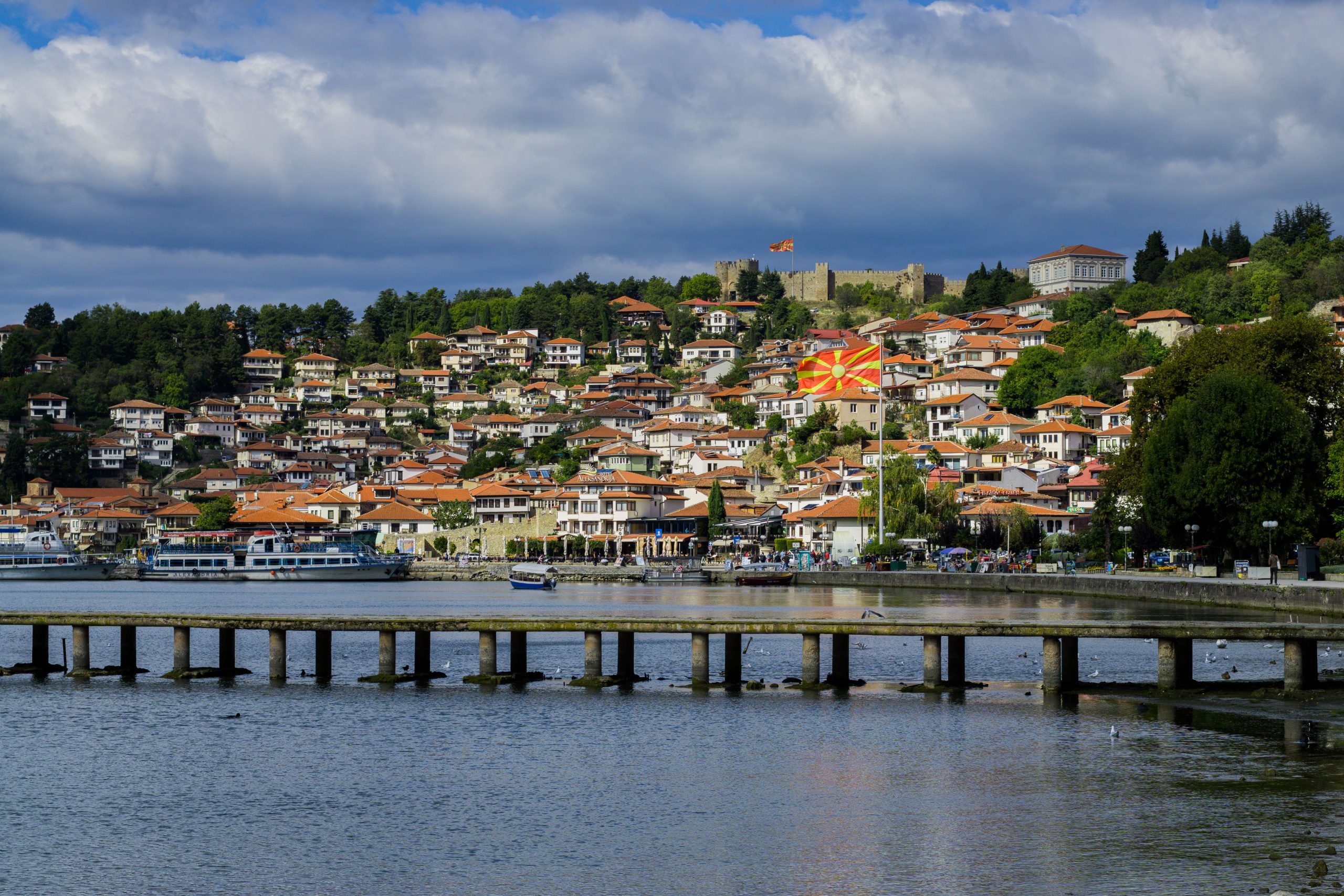 Picturesque Ohrid town with a Macedonian flag overlooking the lake and pier.