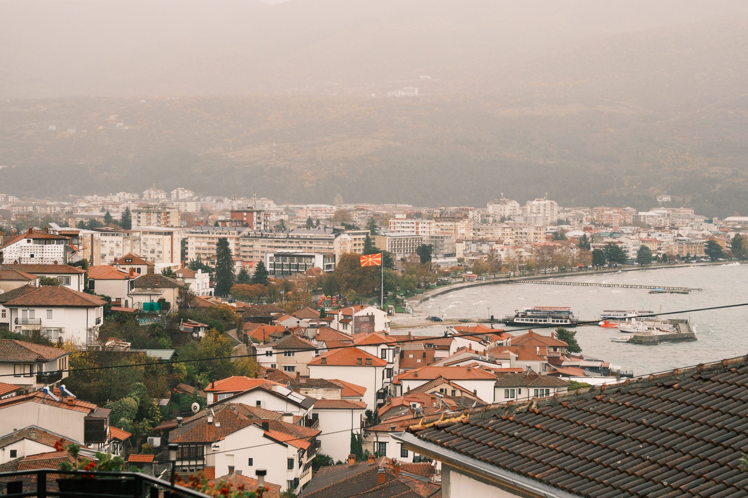 Scenic aerial view of Ohrid city with Macedonian flag and Lake Ohrid in autumn.