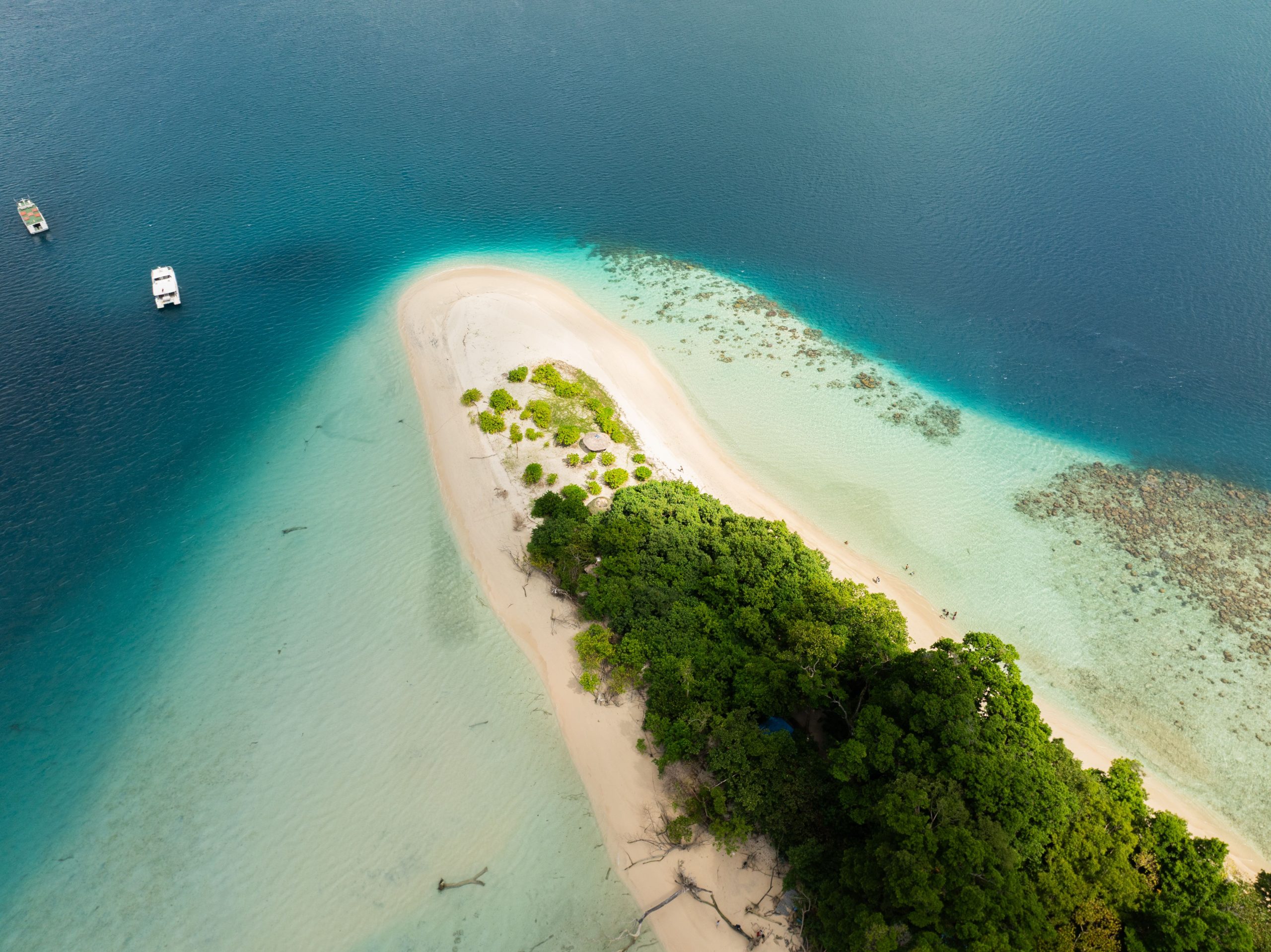 Discover the serene beauty of Jolly Buoy Island's white sandy beach and turquoise waters from above.