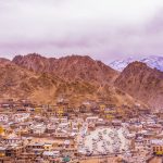 Colorful town surrounded by majestic mountains under overcast sky, showcasing breathtaking natural beauty.